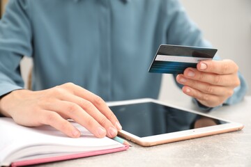 Canvas Print - Man with credit card using tablet at light table indoors, closeup