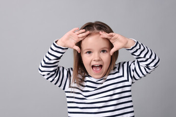 Wall Mural - Portrait of emotional little girl on grey background