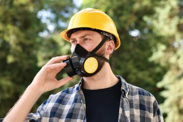 Wall Mural - Man in respirator mask and hard hat outdoors. Safety equipment