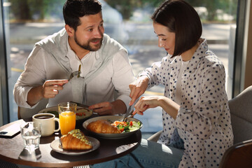 Wall Mural - Happy couple having tasty breakfast in cafe