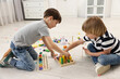 © New Africa - Cute little children playing with wooden blocks on floor indoors