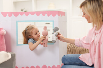 Canvas Print - Puppet theatre. Girl playing toys with her mother at home