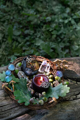 candle, moon amulet, minerals, acorns, oak leaves, mushrooms in forest, natural background. forest harvest. magic crystal ritual, witchcraft. spiritual esoteric wiccan or druids practice.