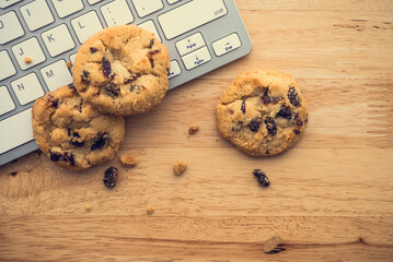 Flat lay of white chocolate chip cookies on keyboard computer on wooden table background copy space. Cookies website internet homepage policy accpeted or blocks concept.