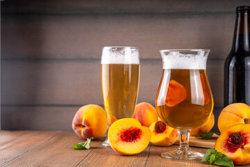 Wall Mural - Glasses with Sour Sweet fruit Peach Craft Beer or Ale on wooden table with fresh peach slices
