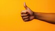 © MrHamster - Close-up of a Person's Hand Giving a Thumbs-Up Gesture Against a Vibrant Yellow Background
