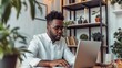 © AlfaSmart - Businessman sitting at a home office desk, focused and working on his laptop