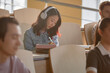 © Seventyfour - Disinterested Asian female student in headphones listening to music while drawing in notebook in lecture hall at university, copy space