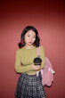 © Seventyfour - Vertical portrait shot of serious Asian female college student with backpack looking at camera while holding reusable cup of coffee isolated on pinkish red background in studio, copy space