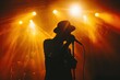 © Anna - Silhouette of a musician with a hat singing into a microphone on stage, illuminated by vibrant orange