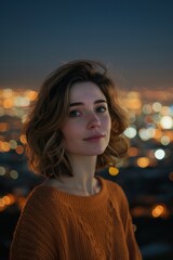 Wall Mural - A woman looks at the camera in an orange sweater. City lights in the background.