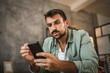 © Miljan Živković - Portrait of adult furious man sit on chair and text sms on cellphone
