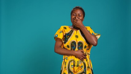 Wall Mural - Woman feeling extremely tired and yawning against blue background, overworked young adult dealing with sleep deprivation in studio. Exhausted fatigued adult with burnout. Camera B.