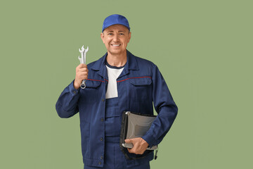 Sticker - Portrait of male mechanic with laptop and tools on green background