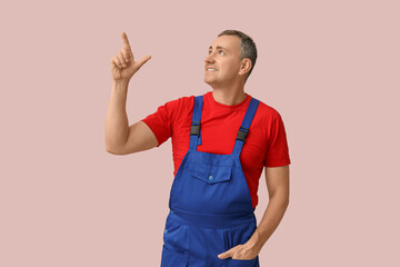 Canvas Print - Portrait of male mechanic pointing up on pink background