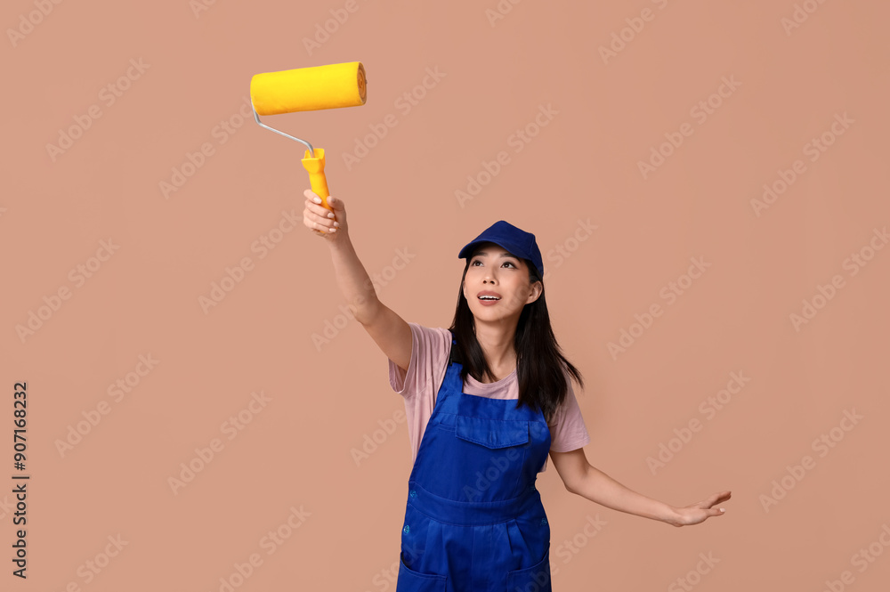 Female Asian painter with roller on brown background
