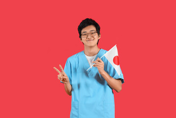 Sticker - Male Asian doctor with flag of Japan showing victory gesture on red background