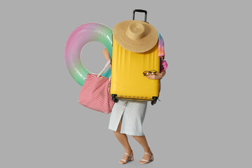 Wall Mural - Young woman with suitcase, bag and  inflatable ring on grey background