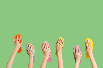 Wall Mural - Hands with colorful flip flops on green background