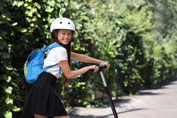 Poster - Cute schoolgirl in helmet with electric scooter outdoors