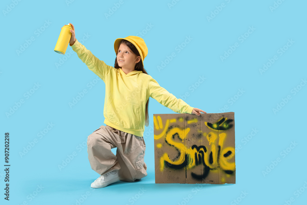 Little girl with spray paint can and graffiti on blue background