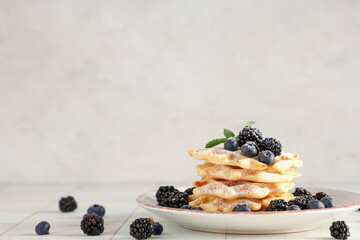 Wall Mural - Delicious Belgian waffles with blueberries, blackberries and sugar powder on plate on table against white background