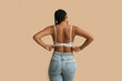 © Pixel-Shot - Young woman in bra on beige background, back view