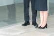 © buritora - オフィスビルにいるスーツを着たビジネスマン男女の足元