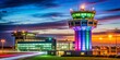 © Wanlop - Vibrant airport control tower shines bright with colorful lights against a dark night sky, surrounded by subtle aircraft movement at Dublin Airport.