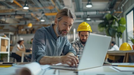 Wall Mural - A skilled architect and engineers examining construction details on a laptop, working together in a modern, open-plan office