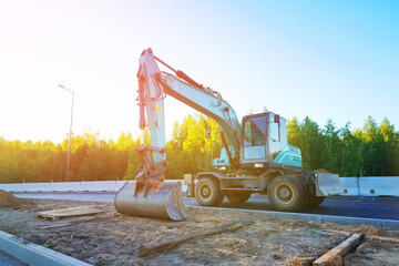 Excavator on road construction. Screeding ground for installing borders, curbs concrete blocks at road. Roadworks, construction site. Bucket wheel excavator on road construction at construction site.