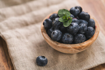 Wall Mural - Fresh blueberries in wood bowl on table with napkin slightly toned