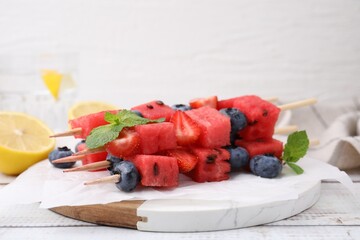 Canvas Print - Skewers with tasty watermelon, strawberries, blueberries and mint on light wooden table, closeup