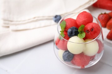 Wall Mural - Tasty watermelon and melon balls with blueberries in glass on white tiled table, closeup. Space for text