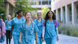 © VK Studio - A group of smiling medical students in blue scrubs walk confidently outdoors, radiating energy and camaraderie.