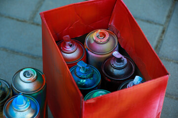 Wall Mural - Many spray paint cans and red cardboard box outdoors, closeup