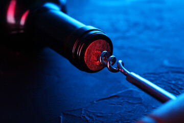 Wall Mural - Wine bottle with corkscrew in lights on table, closeup