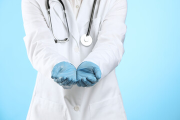 Wall Mural - Doctor holding something on light blue background, closeup