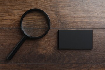 Wall Mural - Blank business cards and magnifying glass on wooden table, flat lay. Mockup for design