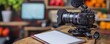 © Tapanut - Professional video camera with microphone and empty notepad on desk, ready for video production in a cozy studio setting with blurred background.