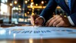 © Chopang.studio - Business professional writing notes on financial documents in a modern office environment with warm lighting.