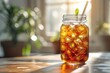 © Vilaysack - A refreshing iced tea in a mason jar with a straw on a sunlit table. The background features green plants soft-focused due to sunlight.