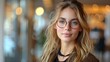 © Vilaysack - Portrait of a young woman with glasses in a cozy indoor setting with a blurry, warm background. Perfect for lifestyle or professional themes.