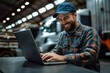 © Rajiv - Happy mechanic using laptop while working at truck repair workshop, Generative AI