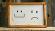 © AiiNa - Whiteboard with a happy face icon and a sad face icon, contrasting emotions