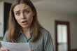 © polack - European shocked woman reads bad news in letter in looking at camera. Emotion of grief, bank debt, bankruptcy