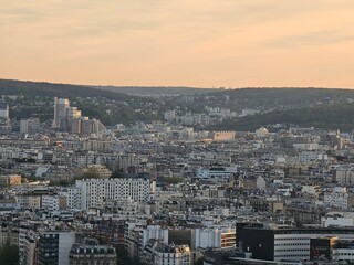 Wall Mural - Paris, France - April 12, 2024: Aerial view to the city of Paris, during the golden hour between modern skyscrapers and old buildings. Beautiful sunset over the city reflected on the buildings.