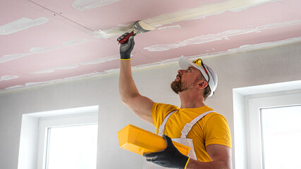 Wall Mural - The worker make a plasterboard ceiling. He does taping plaster drywall ceiling joints. He is using special stainless steel taping knife.