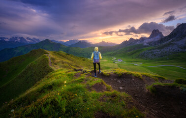 Wall Mural - woman with backpack on the trail and beautiful alpine mountain peaks at colorful sunset in summer. p