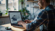 © TyliJura - Engineer working on a laptop with technical drawings of mechanical components, demonstrating focus and technical skills in a professional workspace, ideal for technology and engineering themes